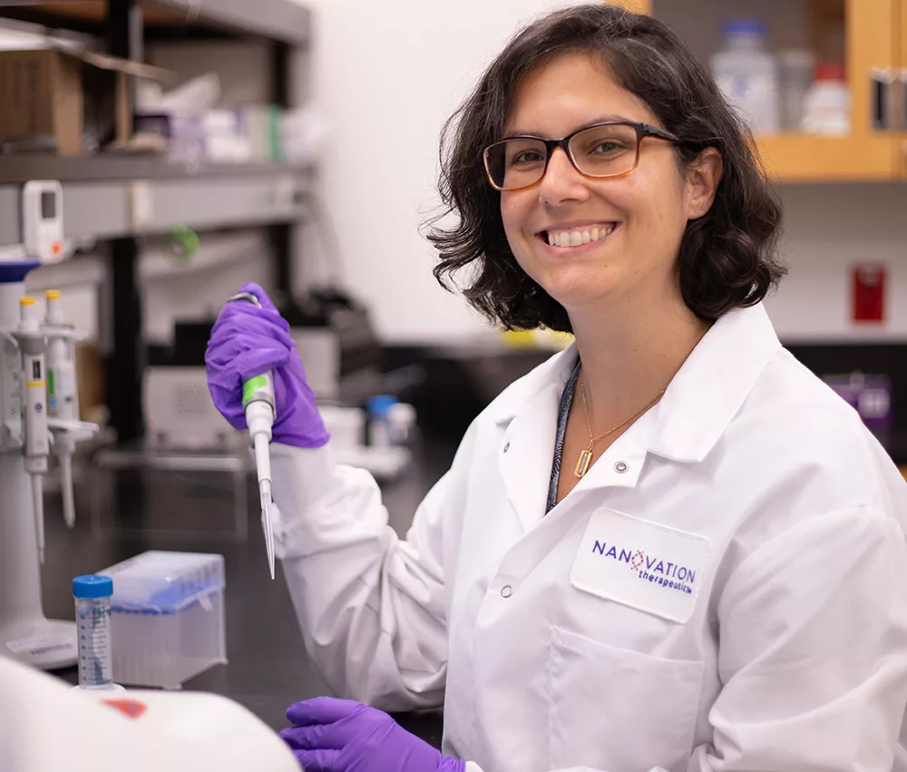 livia-lab Woman scientist wearing safety goggles, lab coat and NanoVation-branded face mask